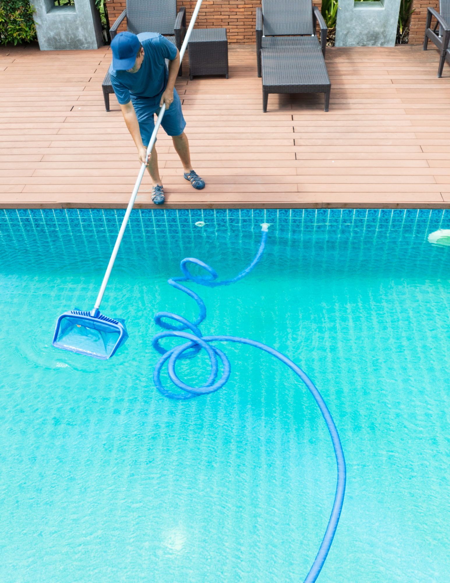 pool technician cleaning a pool with a net and vacuum
